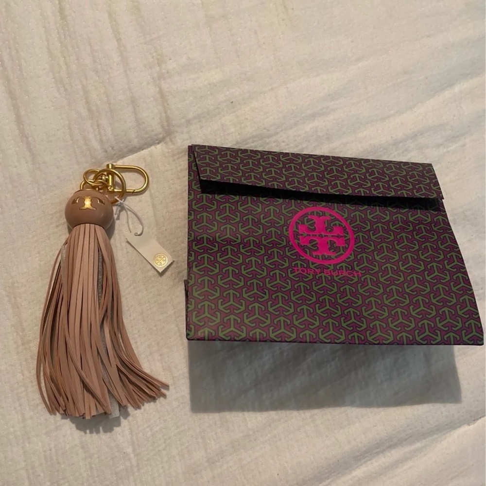 Tory Burch tassel with hidden phone charger. Very pretty pink color. NWT